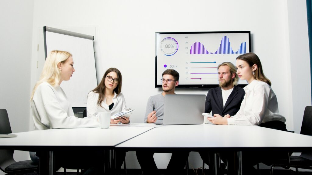 A group of professionals engaged in a business meeting with data presentation.