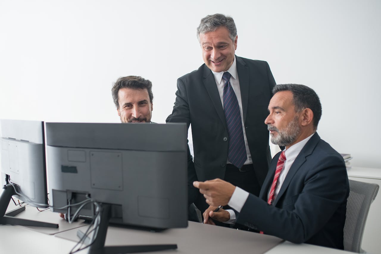 Three business colleagues in suits happily collaborating at the office.